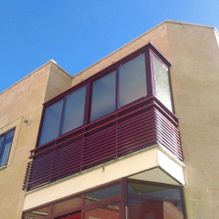 Aluminios Carsan parte de una casa de color amarillo con ventanas rojas